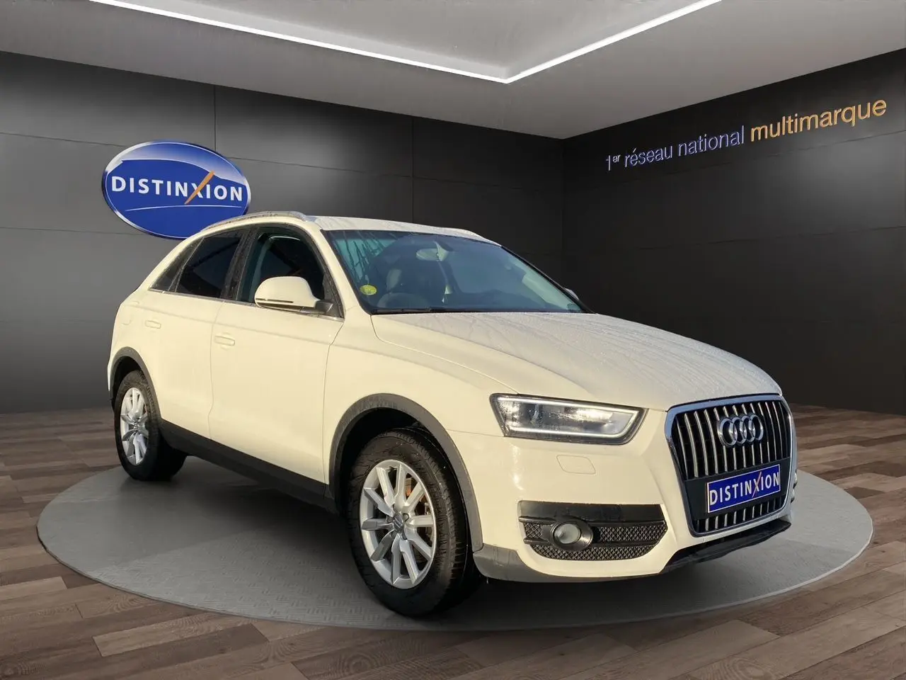 Audi Q3 blanc en 3/4 avant droit avec vitres arrière surteintées, présenté en showroom Distinxion.