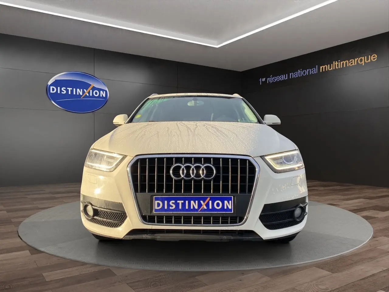 Audi Q3 blanc vue de face avec calandre chromée et logo quatre anneaux, en showroom Distinxion.