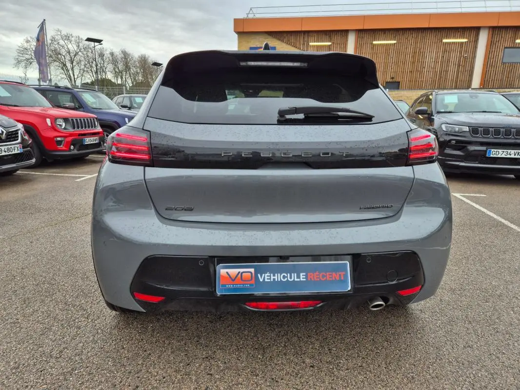 Vue arrière d'une Peugeot 208 Hybrid 110 gris, avec feux LED allumés et logo Peugeot visible sur le hayon.