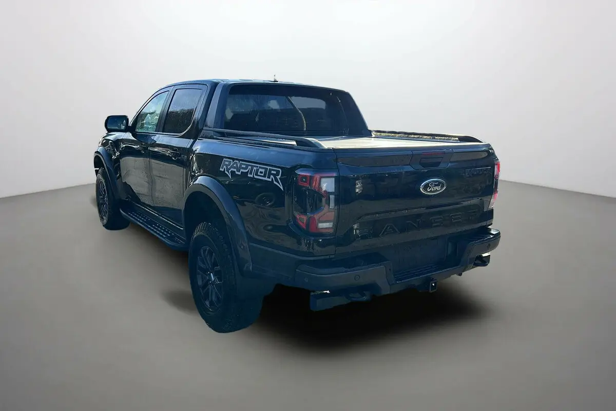 Ford Ranger Raptor noir absolu vu 3/4 arrière droit, avec logo Raptor sur la benne et jantes noires.