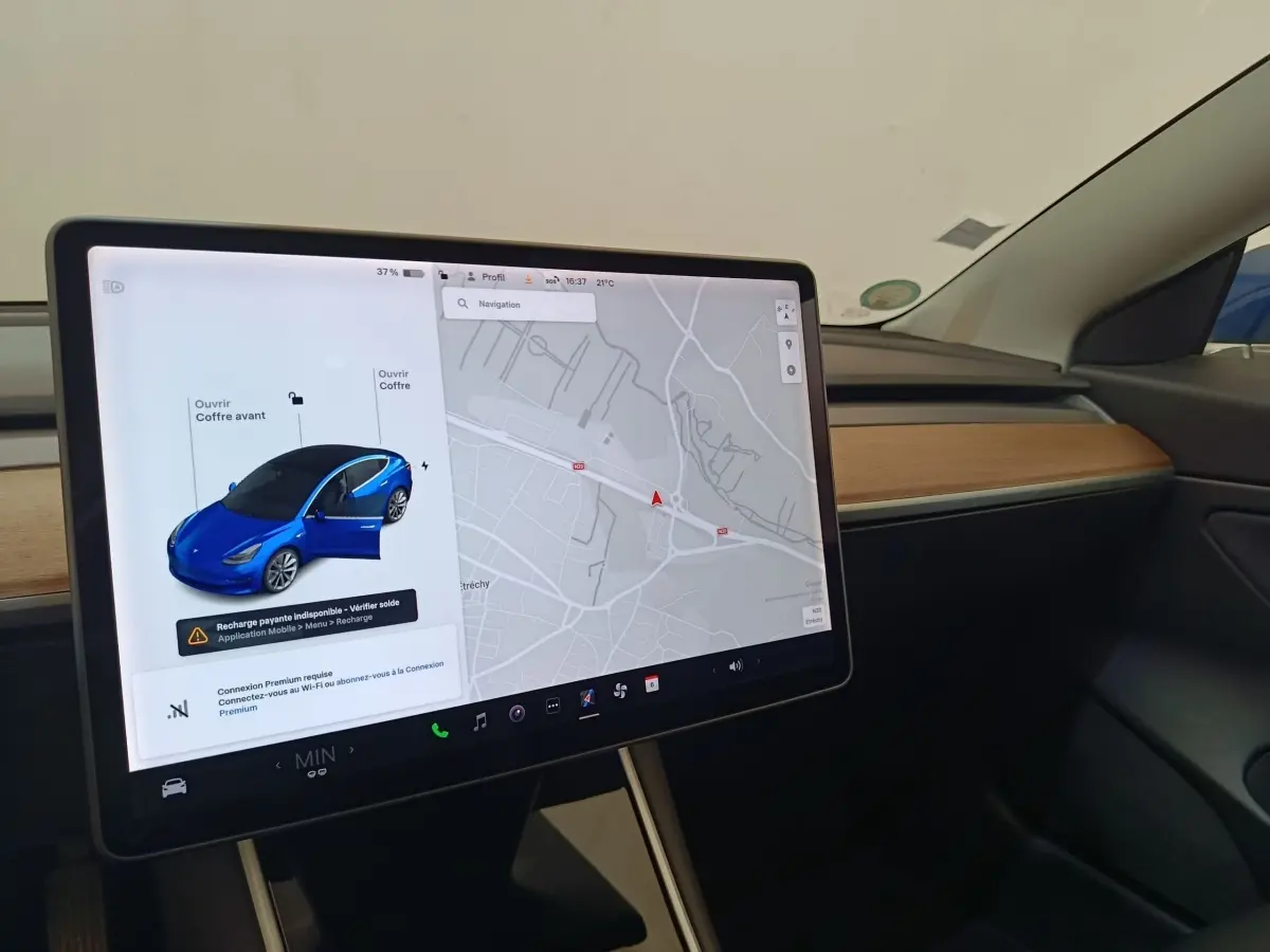 Écran tactile central affichant la navigation et une Tesla Model 3 bleue vue de 3/4 avant avec porte ouverte.