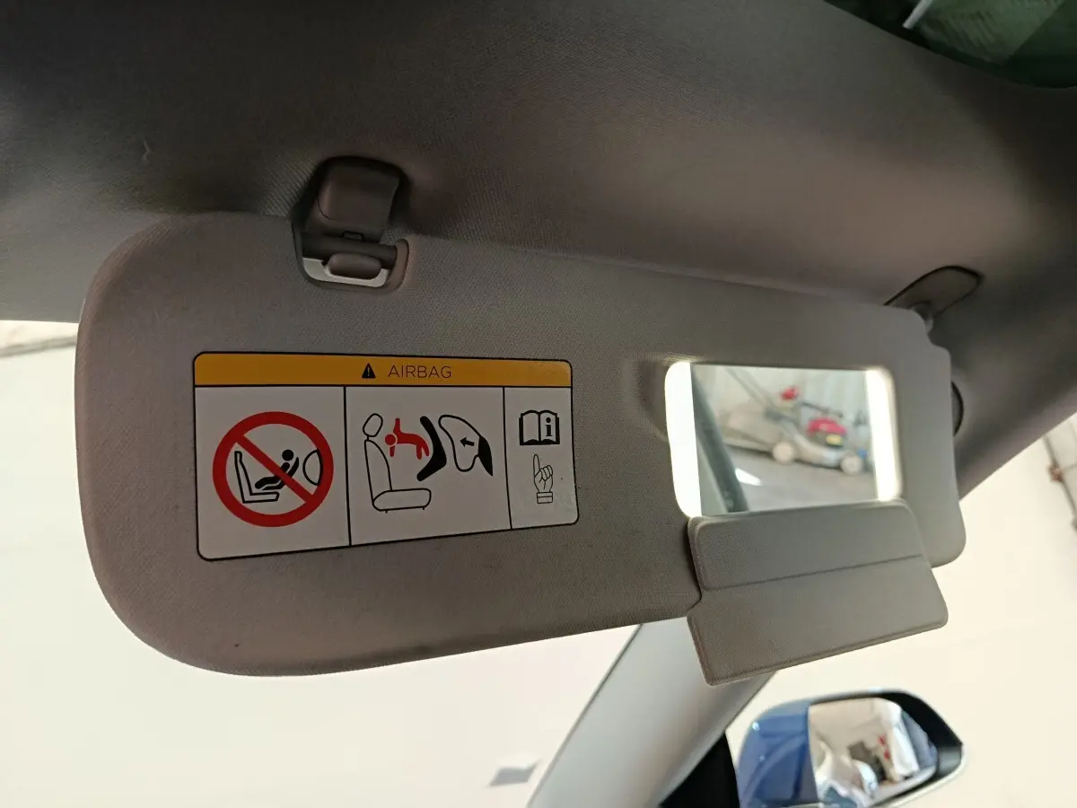 Détail du pare-soleil côté conducteur avec miroir intégré et avertissement airbag dans une Tesla Model 3 bleu.