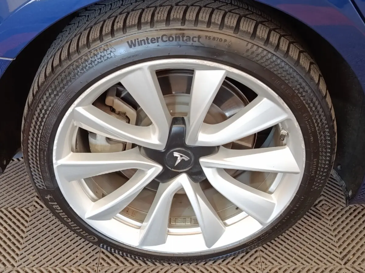 Gros plan sur la roue avant droite d'une Tesla Model 3 Long Range bleu, avec pneu hiver et passage de roue visible.
