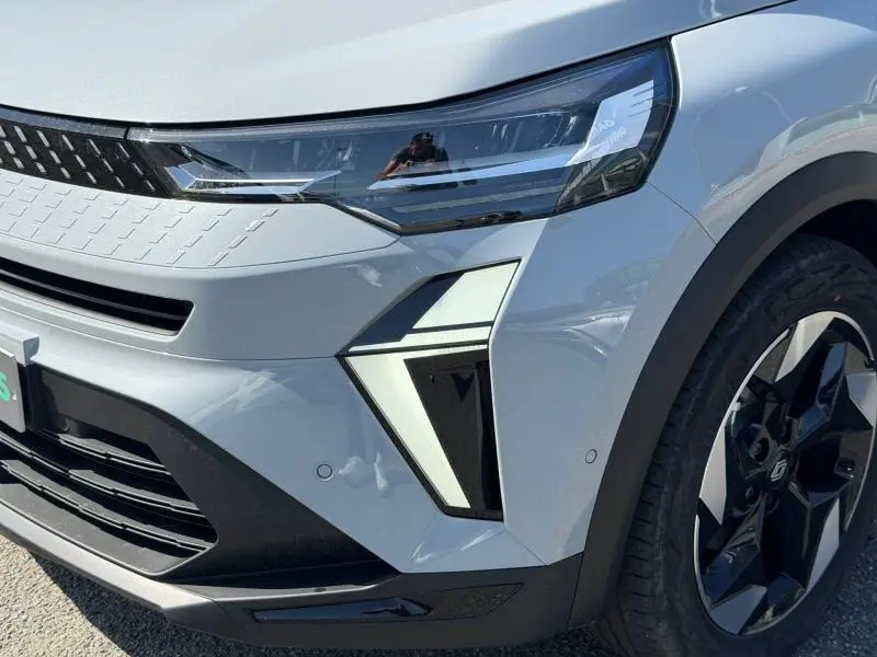 Gros plan sur l'avant droit du Renault Captur gris Rafale métallisé, mettant en valeur le phare LED et la jante alu noire.