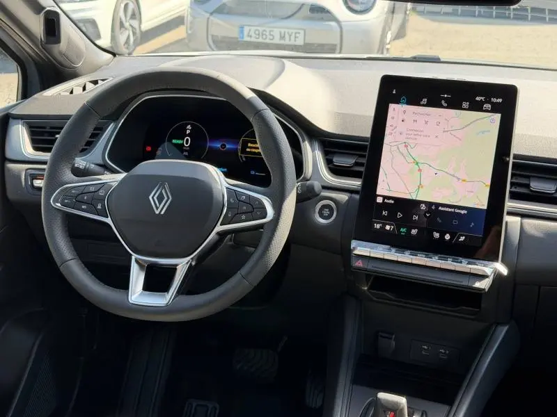 Vue intérieure avant du Renault Captur 1.8 E-Tech gris Rafale, avec volant multifonction et écran tactile vertical.
