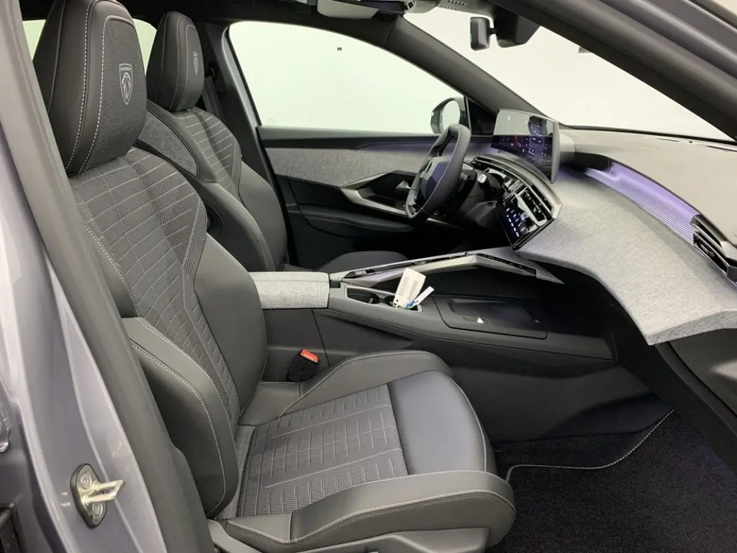 Vue intérieure côté conducteur du Peugeot 3008 1.2 Hybrid 145 GT avec sièges noirs et tableau de bord gris clair.