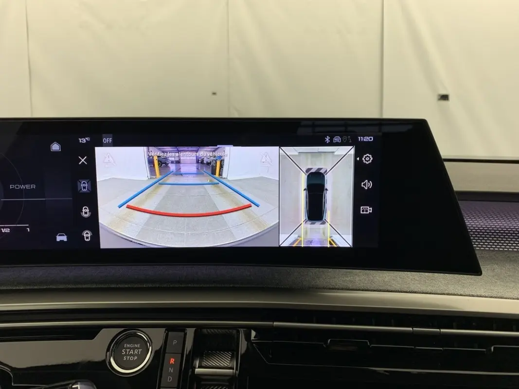 Écran tactile intérieur du Peugeot 3008 montrant l’aide au stationnement avec vue arrière et vue aérienne du véhicule.