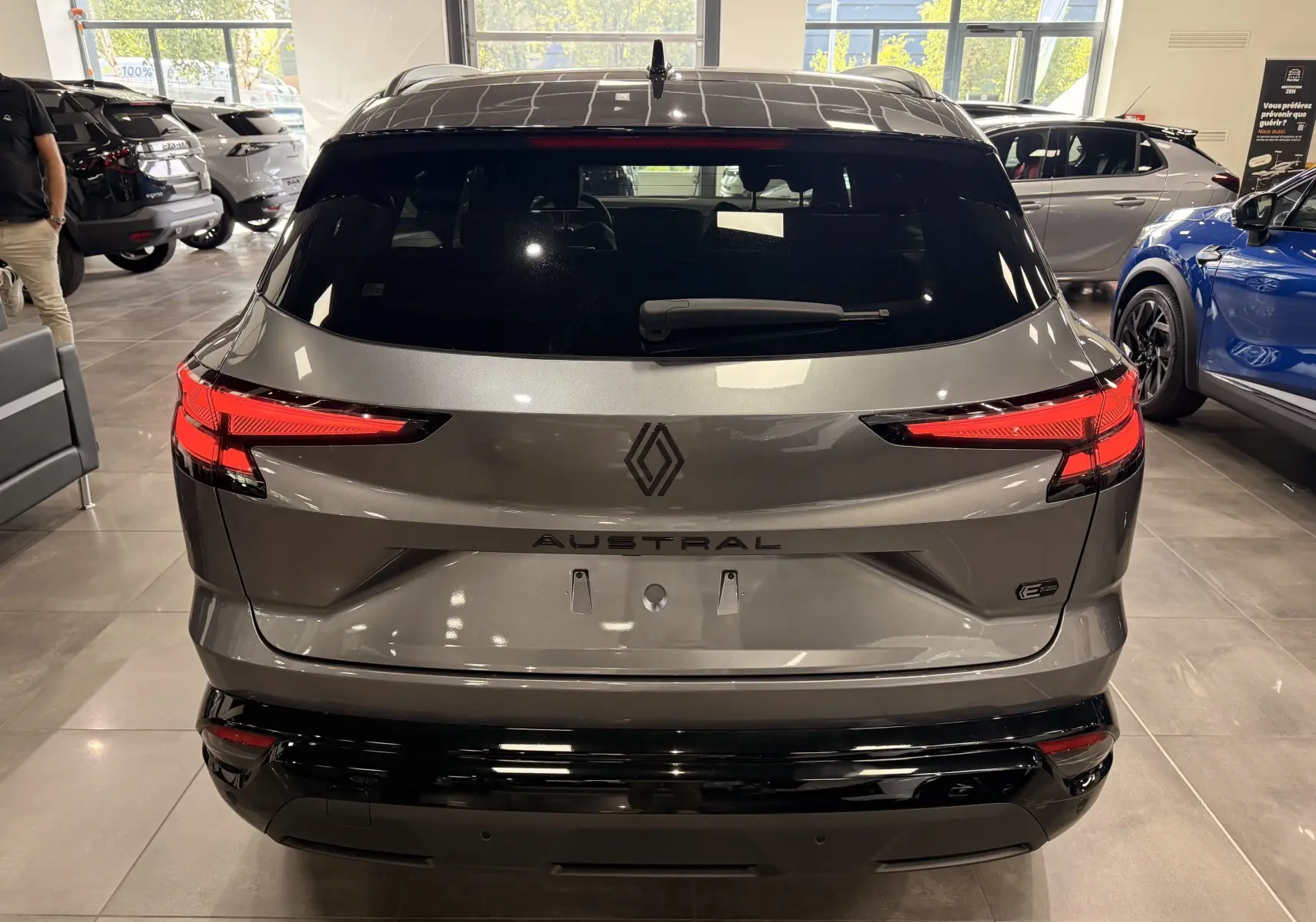 Vue arrière d’un Renault Austral gris schiste avec toit noir, feux LED distinctifs et logo central en concession.