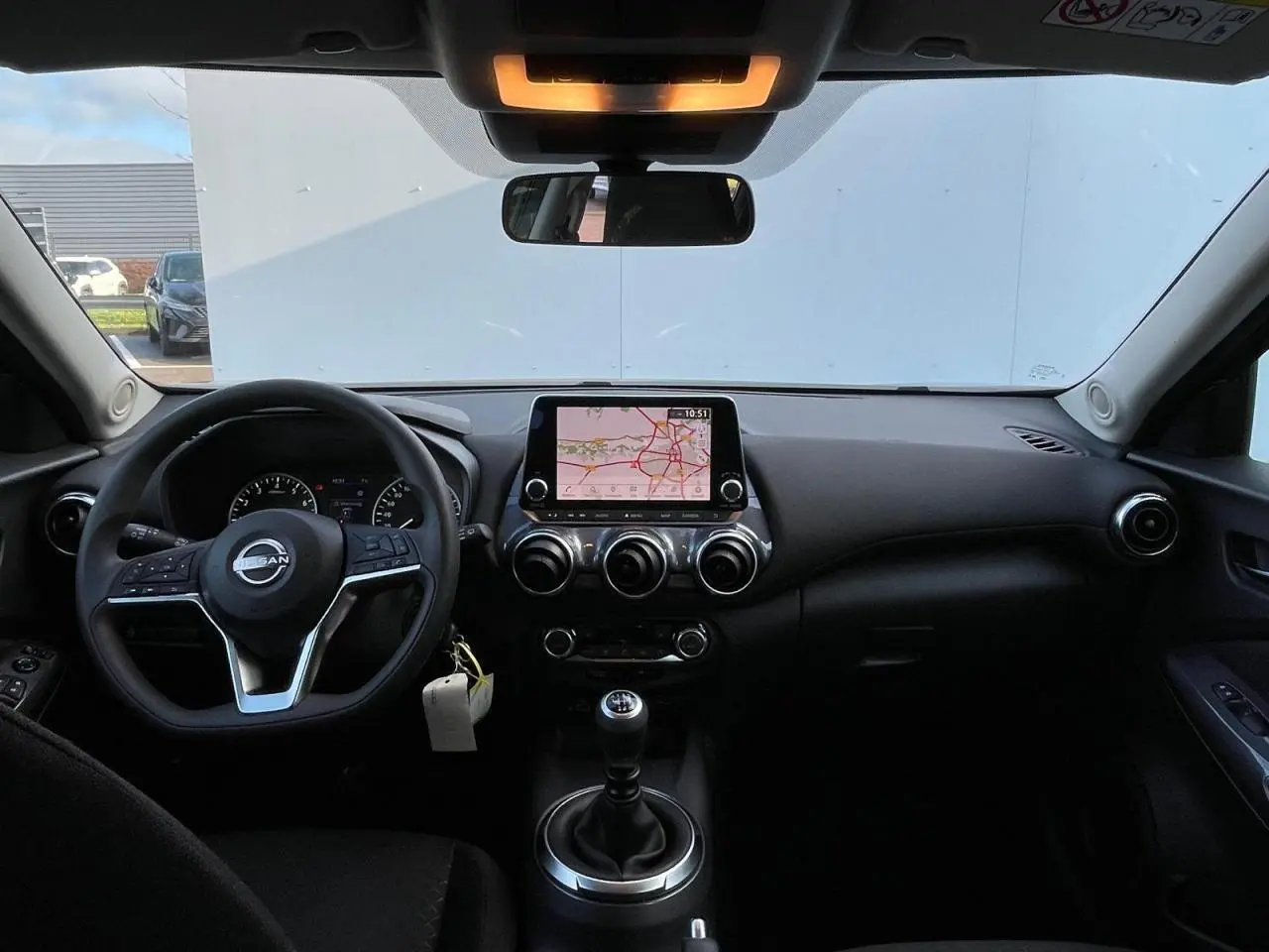 Intérieur avant du Nissan Juke 2024 gris Ceramic, vue du tableau de bord avec écran tactile et volant cuir.