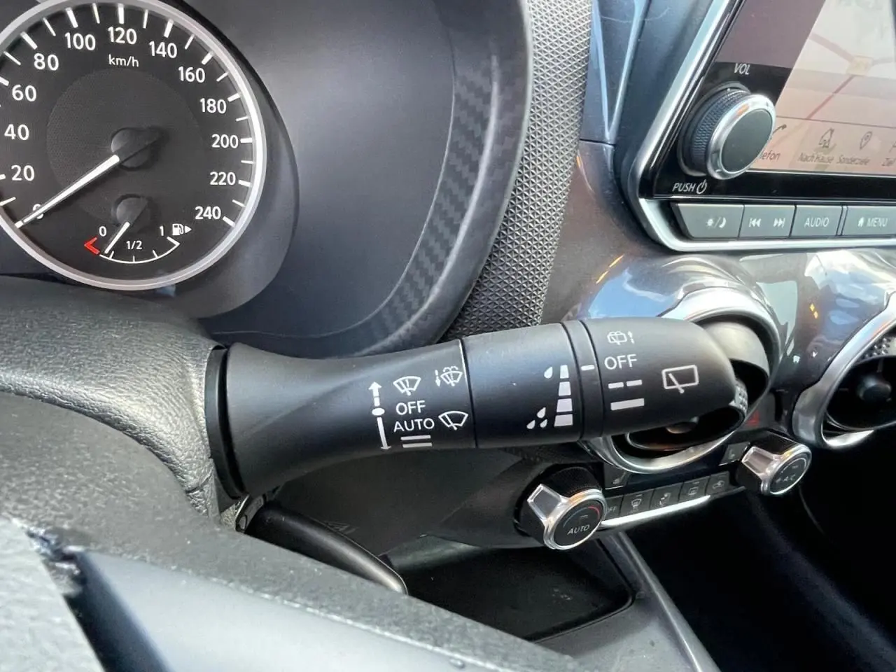 Gros plan sur la commande d’essuie-glace et le tableau de bord noir du Nissan Juke II gris Ceramic 2024.