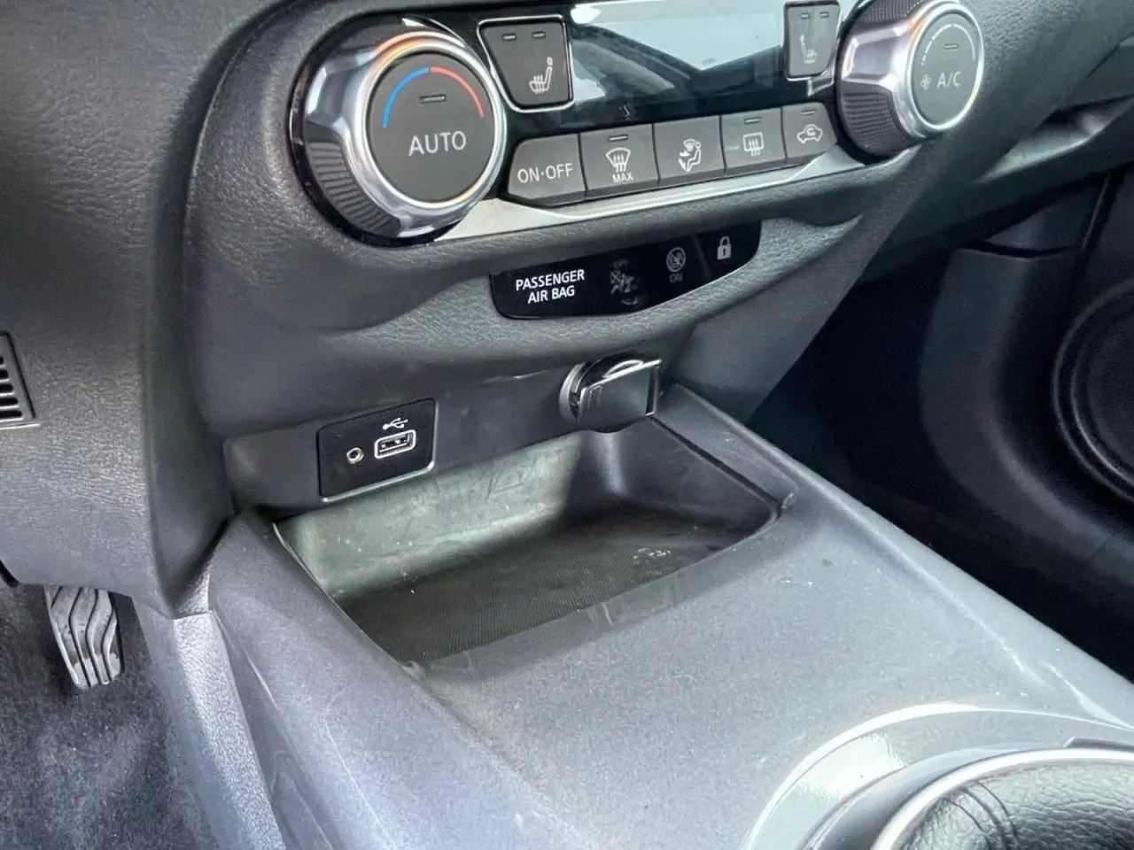 Détail de la console centrale noire du Nissan Juke 2024 avec commandes climatisation et ports USB visibles