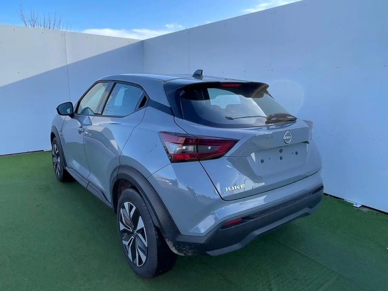 Nissan Juke II gris ceramic vu en 3/4 arrière droit, avec jantes alliage noires et toit noir contrasté.