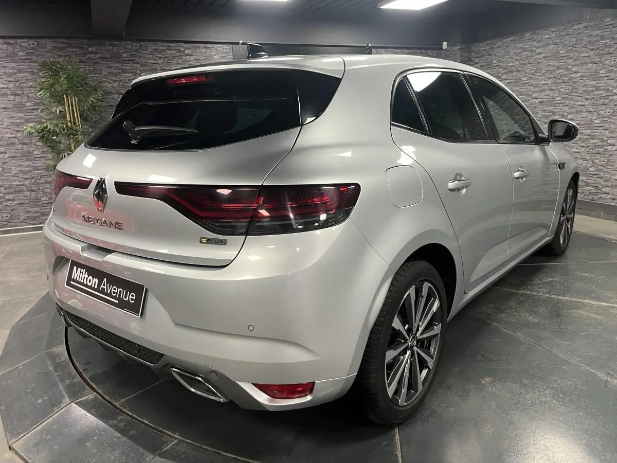 Vue 3/4 arrière droite d'une Renault Mégane gris Highland avec feux LED et double sortie d'échappement chromée.