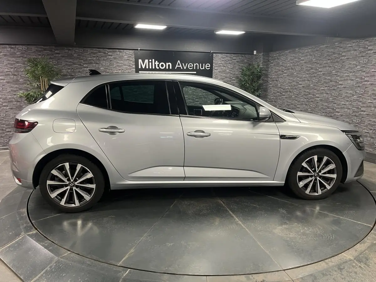 Profil côté gauche d'une Renault Mégane gris Highland 2022 en finition R.S. Line dans un showroom intérieur.