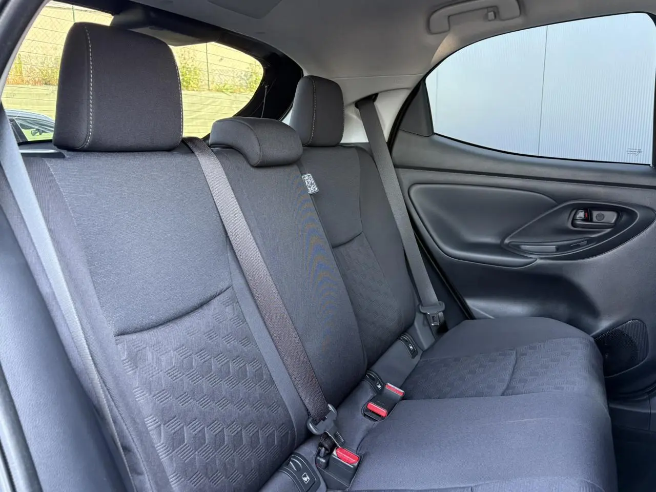 Vue côté droit de la banquette arrière noire avec ceintures et appuie-têtes de la Toyota Yaris Hybride 2025.