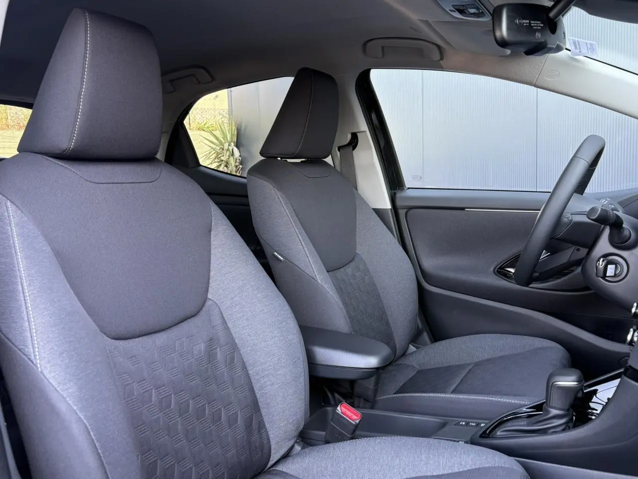 Vue intérieure côté droit des sièges avant gris foncé et clair de la Toyota Yaris Hybride 2025 avec accoudoir central.
