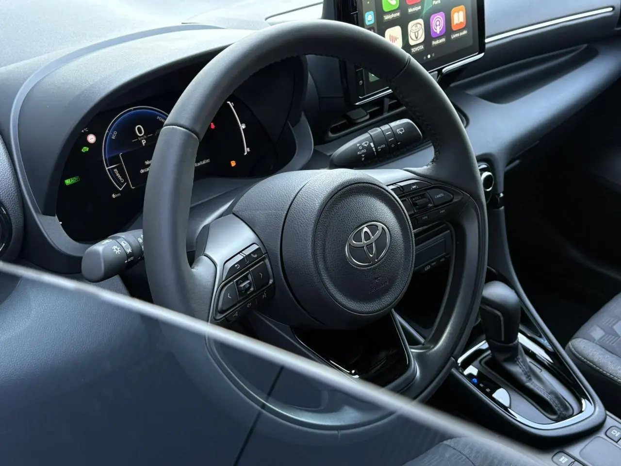 Vue intérieure centrée sur le volant cuir et tableau de bord numérique de la Toyota Yaris Hybride 2025.