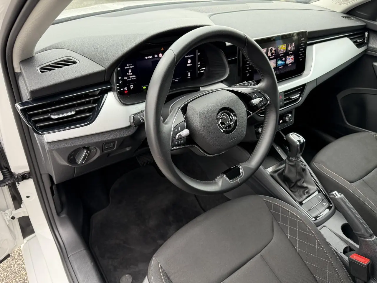 Vue intérieure côté conducteur de la Skoda Scala blanche 2023, avec tableau de bord numérique et écran tactile central.
