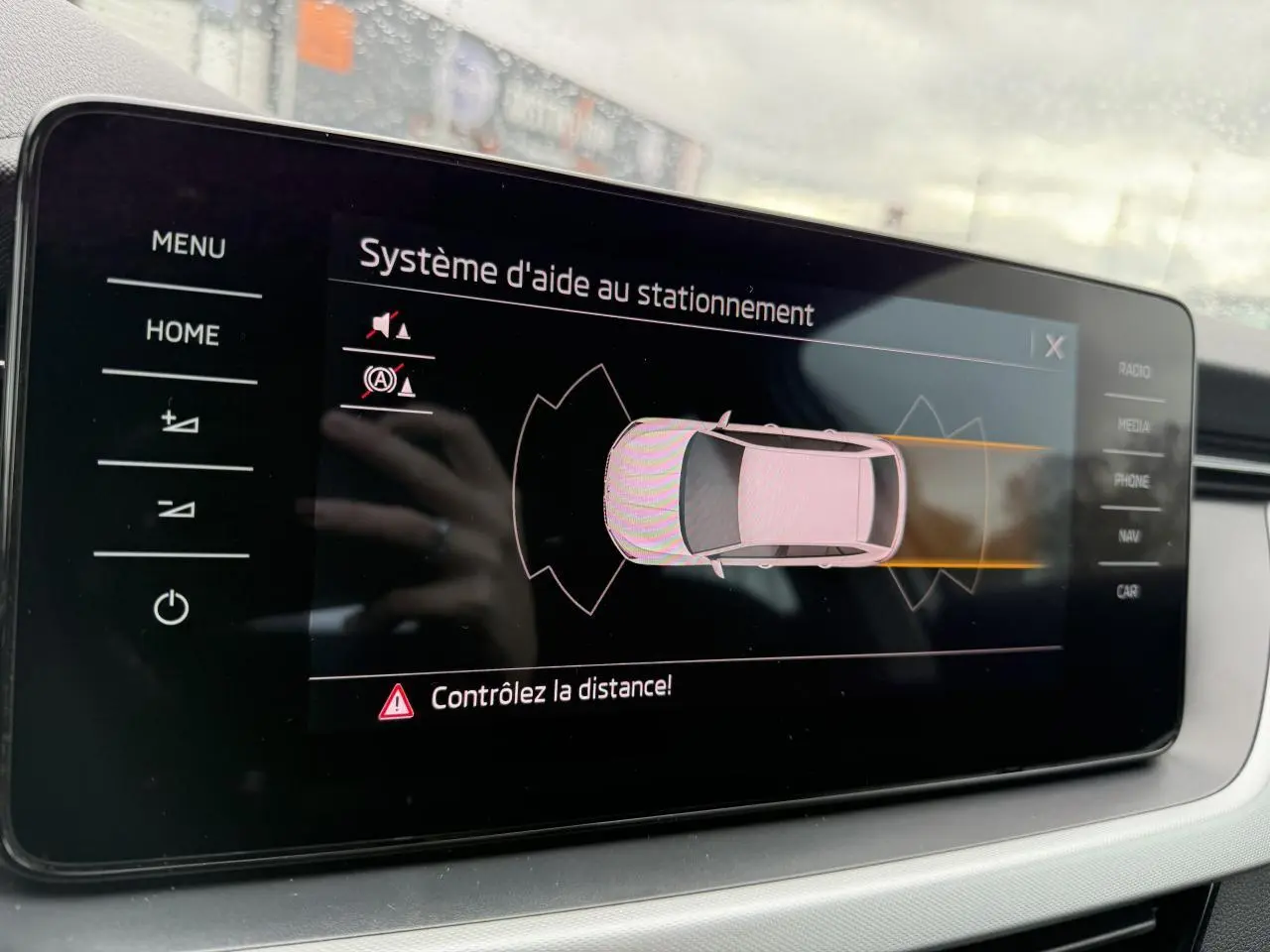 Écran tactile intérieur du système d'aide au stationnement de la Skoda Scala blanche, vue rapprochée du tableau de bord.