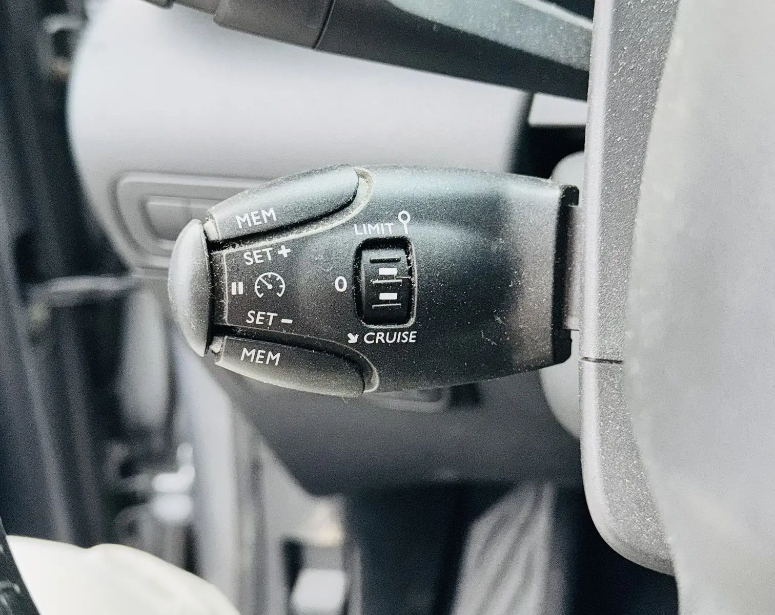 Gros plan sur la commande de régulateur de vitesse à gauche du volant dans l'habitacle du Citroën C3 Aircross gris 2020.