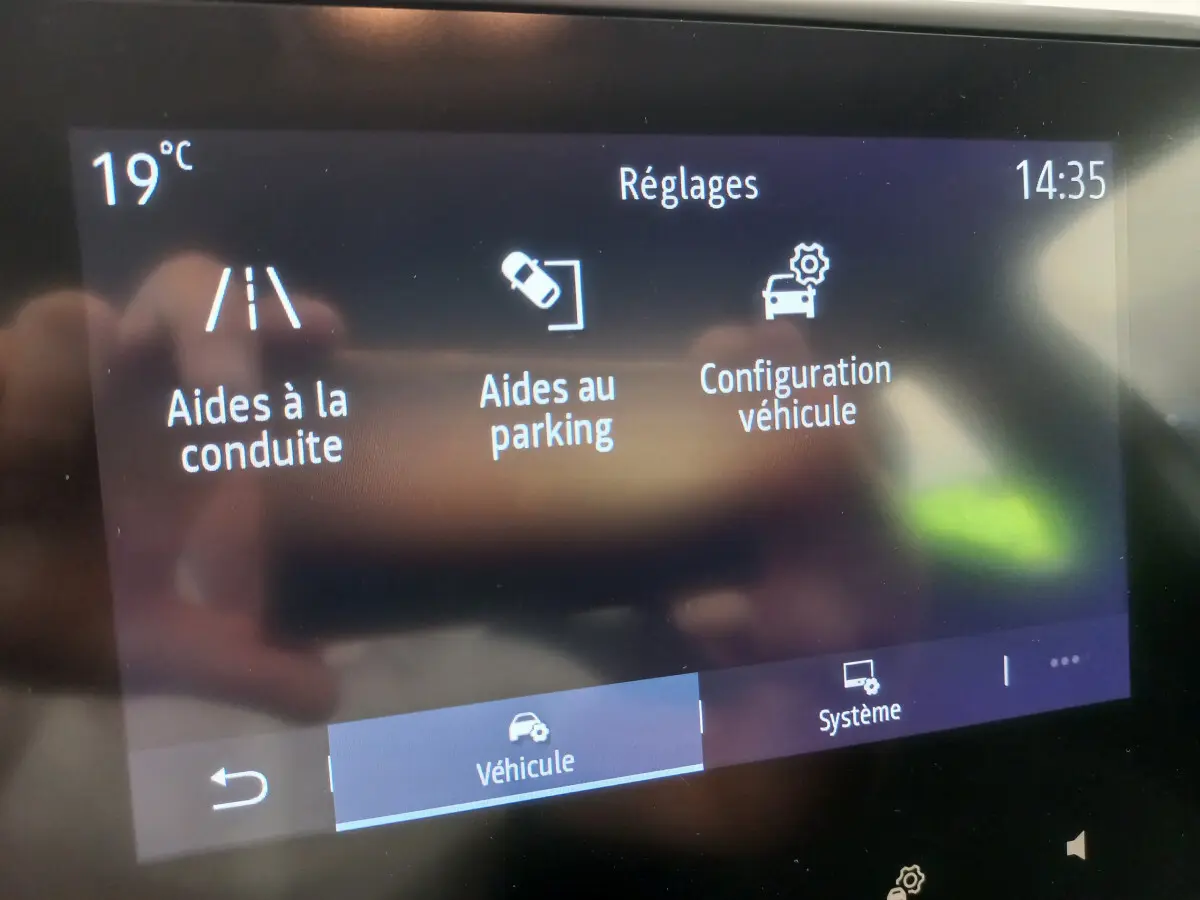 Écran tactile central de la Renault Clio Business blanc affichant les réglages d’aides à la conduite et au parking