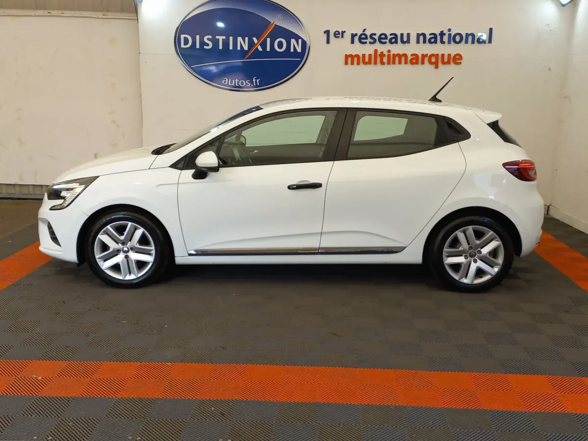 Profil côté gauche d'une Renault Clio Business blanche 2021, avec jantes alliage et poignées noires visibles en intérieur showroom.