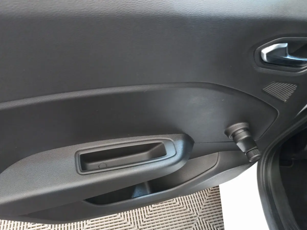 Détail de la porte intérieure côté droit noire de la Renault Clio Business SCe 65 blanche, avec poignée et manivelle de vitre.