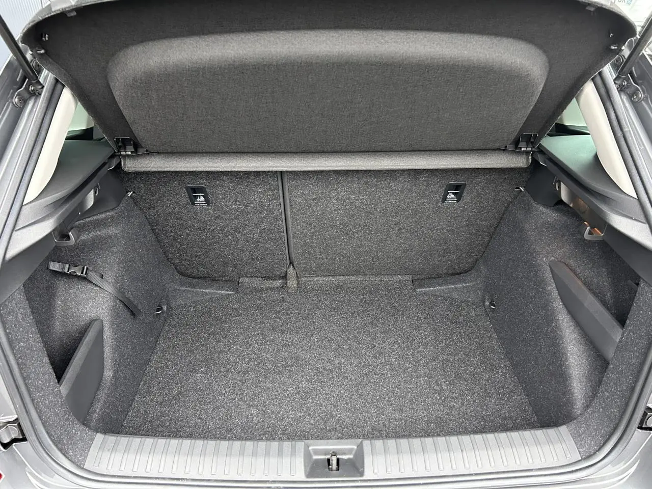 Coffre ouvert vu de l'arrière d'un Skoda Kamiq gris graphite, espace de chargement propre et vide.