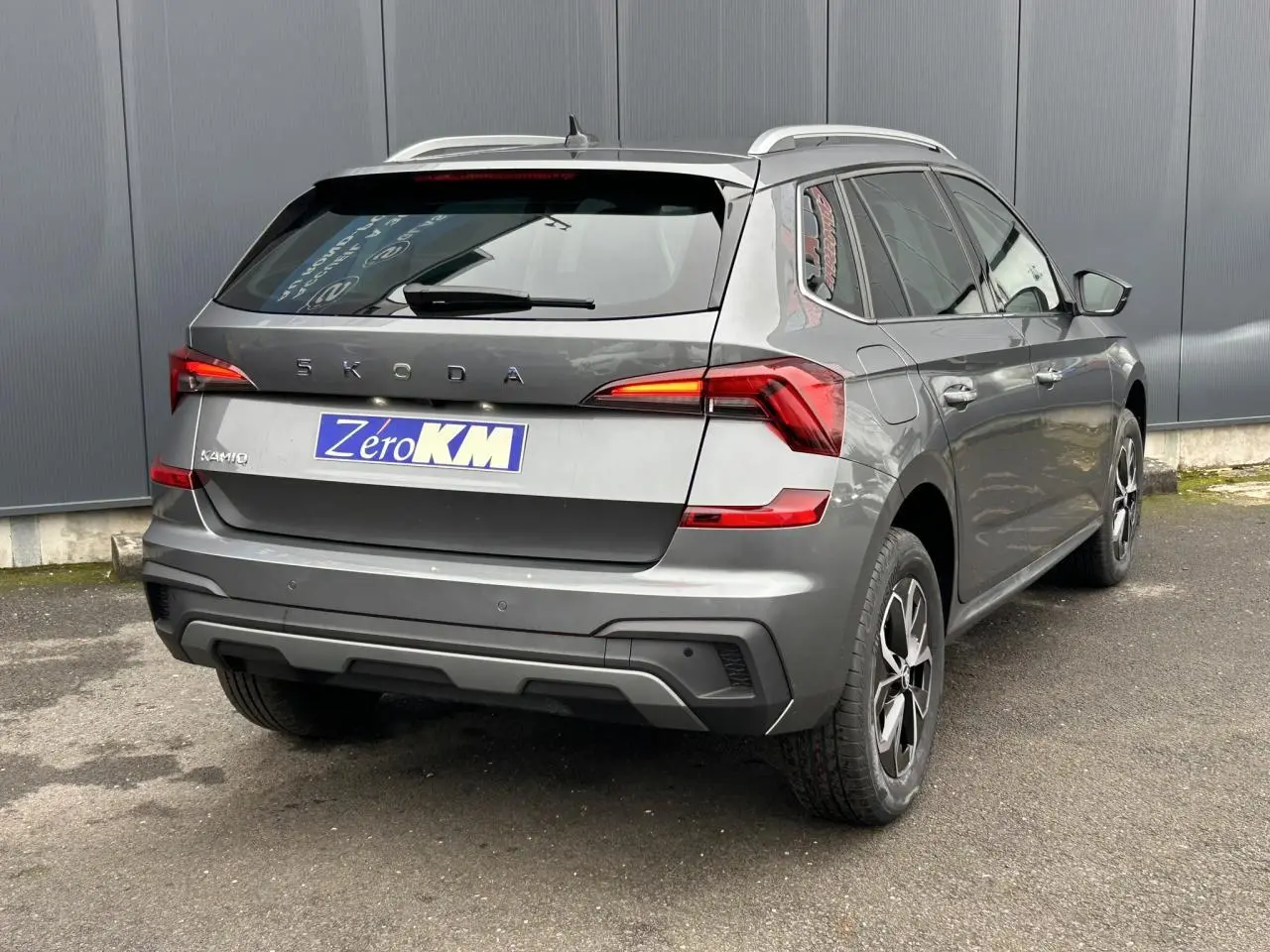 Vue 3/4 arrière droite d'un Skoda Kamiq gris graphite avec jantes alliage et vitres surteintées.