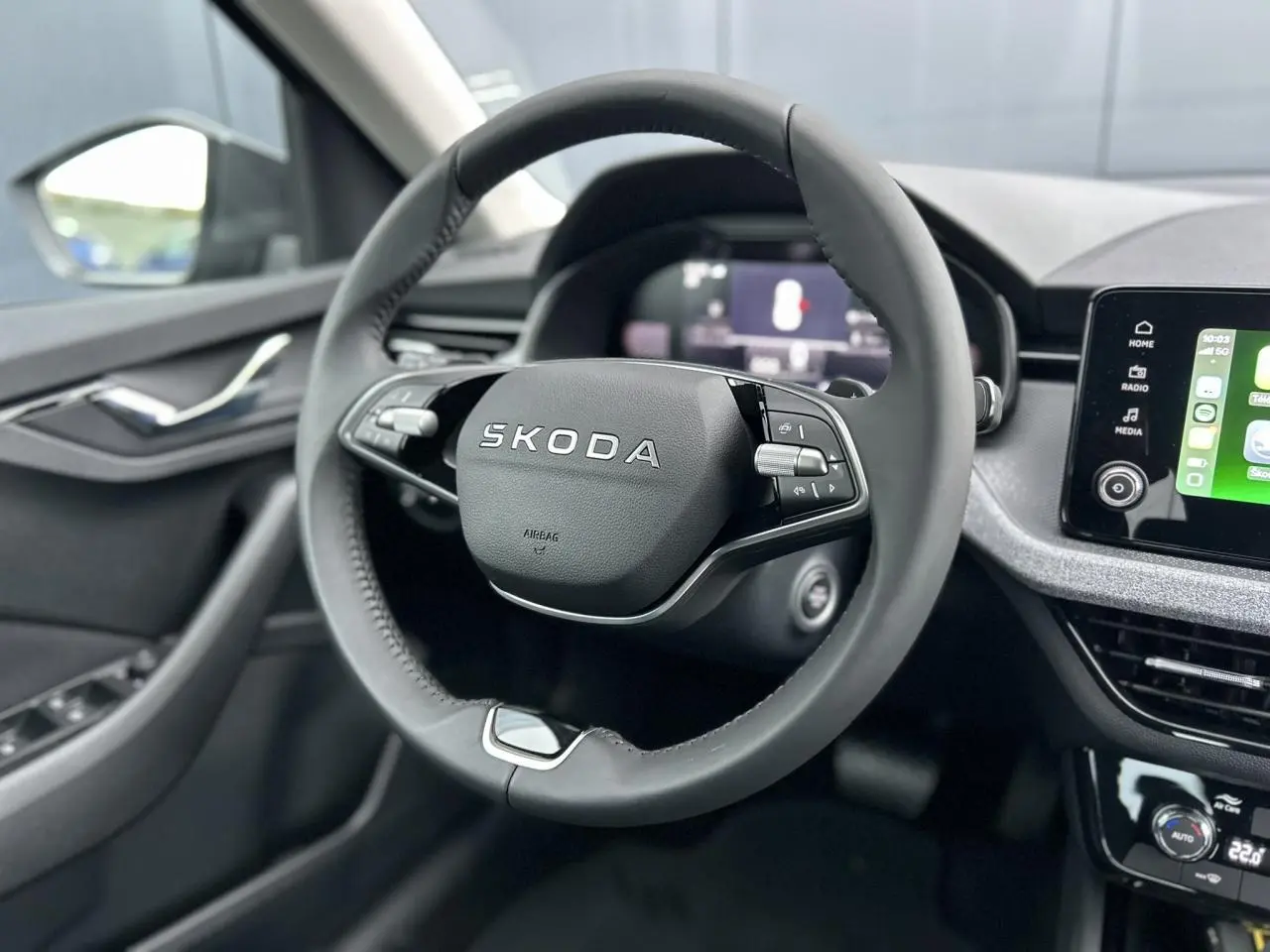 Vue rapprochée du volant cuir noir multifonctions d’une Skoda Kamiq 2025 avec écran tactile et commandes intégrées.