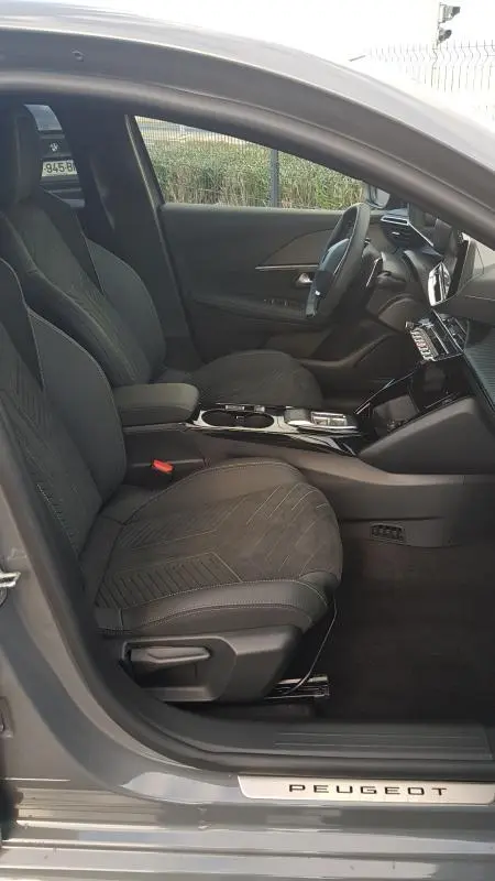 Vue intérieure côté conducteur de la Peugeot 208 Hybrid gris 2025, avec sièges en tissu et cockpit numérique visible.