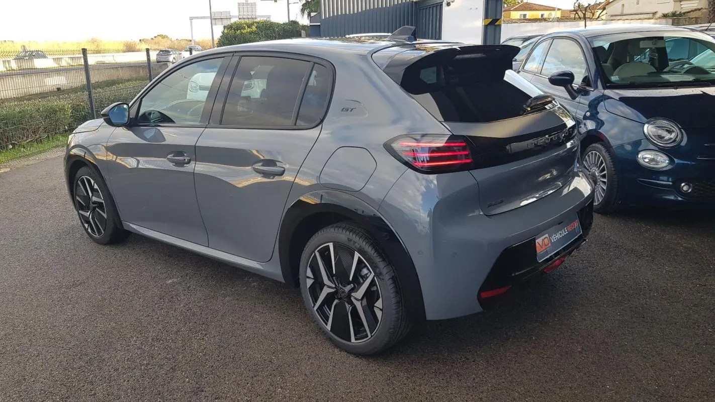 Vue 3/4 arrière droite d’une Peugeot 208 Hybrid 110 GT gris avec jantes alliage 17 pouces et toit noir brillant.