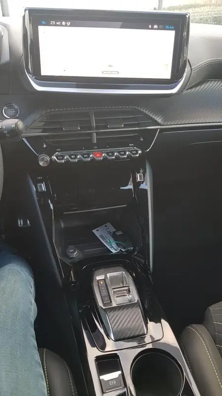 Vue intérieure centrée sur la console centrale de la Peugeot 208 Hybrid 110 e-DCS6 GT 2025, avec écran tactile et levier de boîte auto.