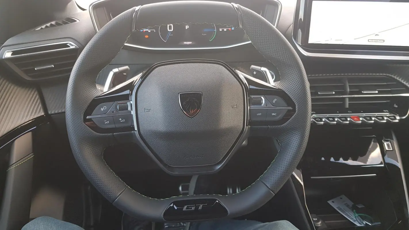 Vue intérieure centrée sur le volant GT noir perforé et le cockpit numérique de la Peugeot 208 Hybrid 110 e-DCS6.