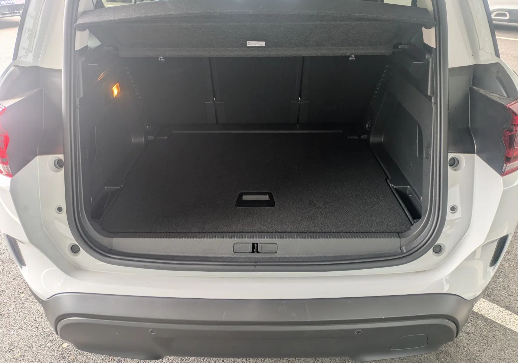 Coffre ouvert vu de l'arrière d'un Citroën C5 Aircross blanc Okenite, montrant l'espace de chargement vide et la plage arrière.