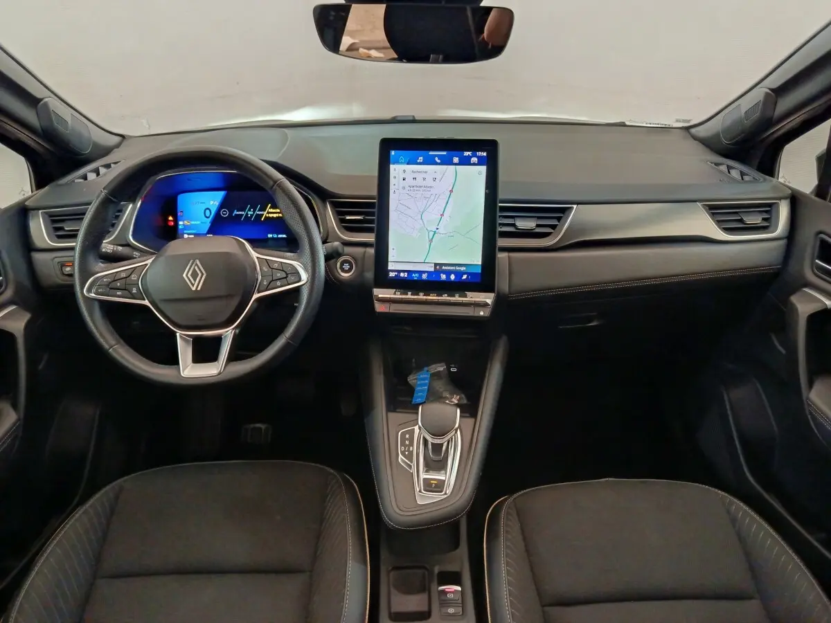 Vue intérieure frontale du tableau de bord noir du Renault SYMBIOZ avec écran tactile vertical et volant multifonctions.
