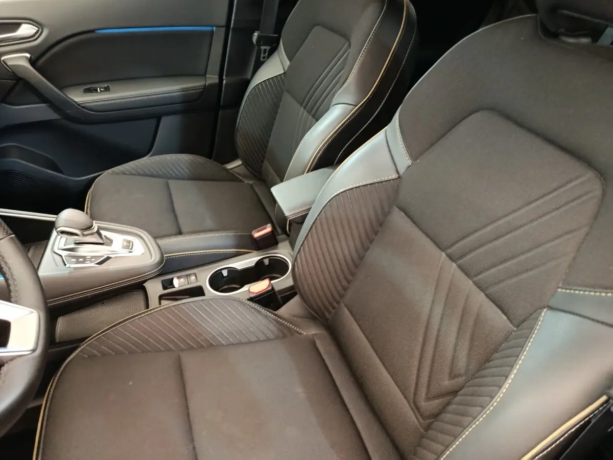 Vue intérieure rapprochée des sièges avant noirs et console centrale avec levier de vitesse de la Renault SYMBIOZ Iconic E-Tech.