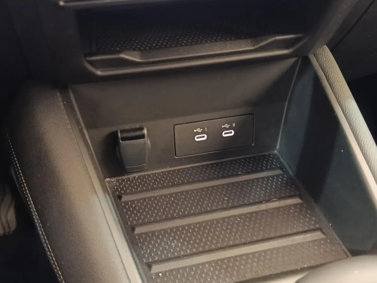 Vue rapprochée de la console centrale noire du Renault Symbioz avec prises USB-C et prise 12V visible.