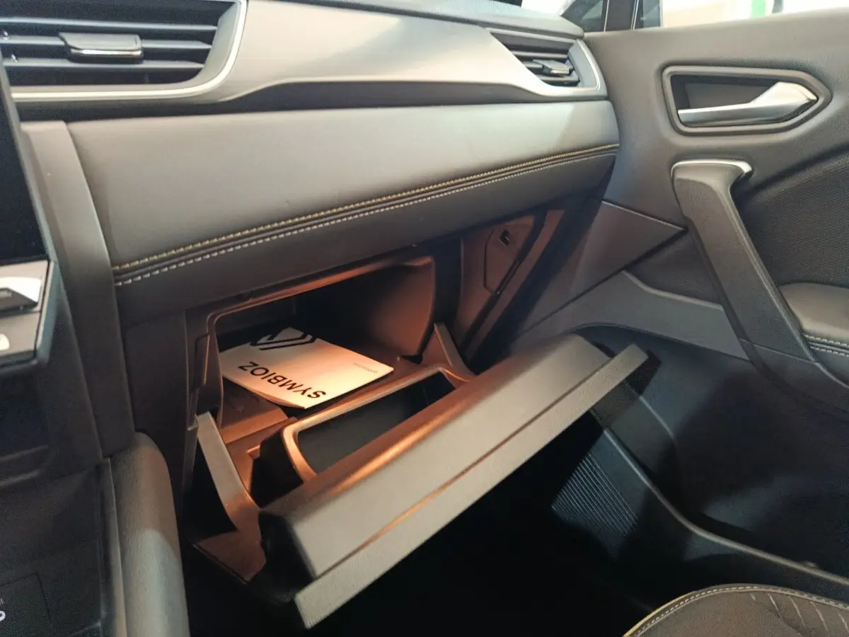 Intérieur côté passager du Renault SYMBIOZ noir, boîte à gants ouverte avec manuel visible.