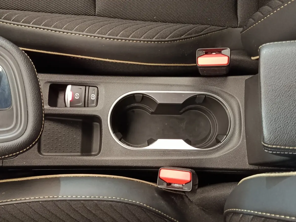 Vue plongeante sur la console centrale noire du Renault Symbioz avec porte-gobelets et bouton frein à main électrique.