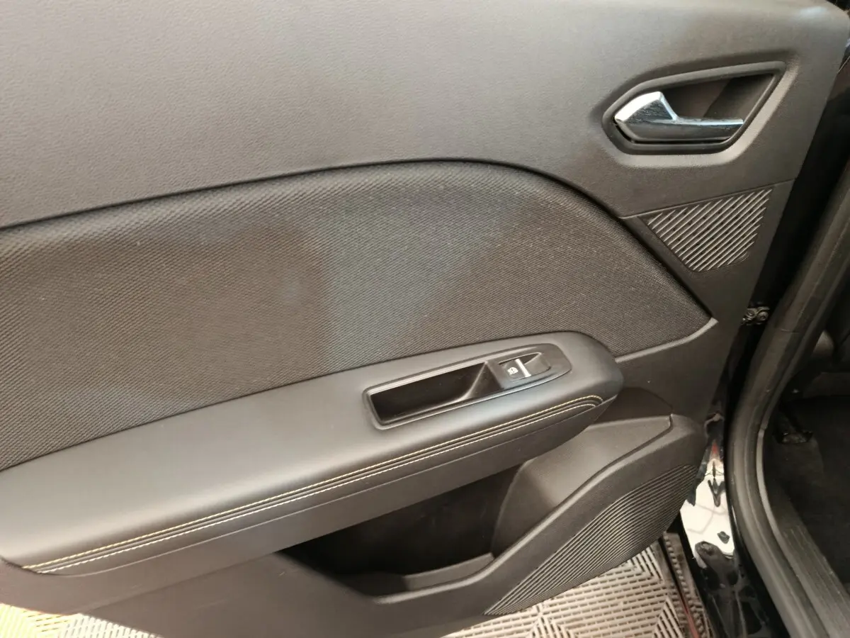 Vue rapprochée de la porte avant droite noire du Renault Symbioz, avec poignée intérieure et commande de fenêtre.