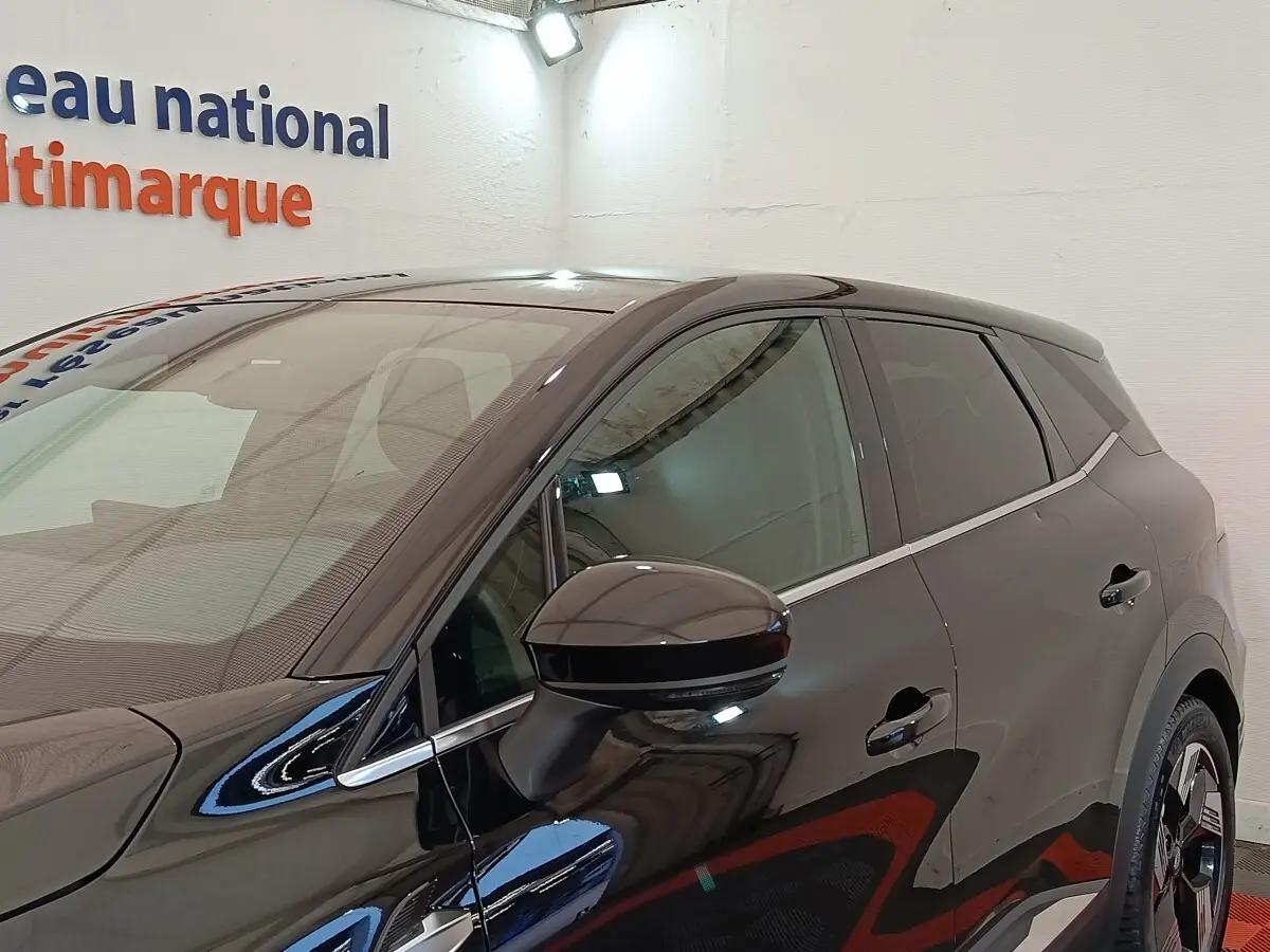 Vue latérale droite d'une Renault SYMBIOZ noire avec rétroviseur et jantes distinctives visibles en intérieur showroom.