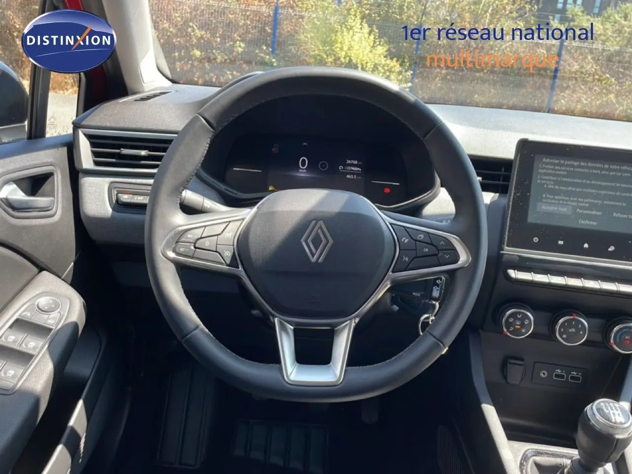 Vue intérieure centrée sur le volant cuir multifonction d'une Renault Clio 2025 avec tableau de bord numérique et écran tactile.