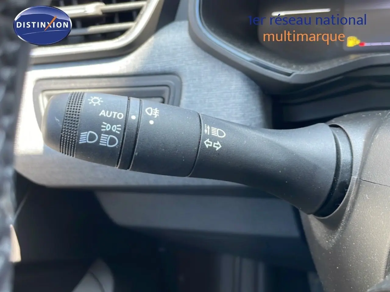 Gros plan sur la commande des phares et clignotants dans l’habitacle d’une Renault Clio rouge flamme 2025.