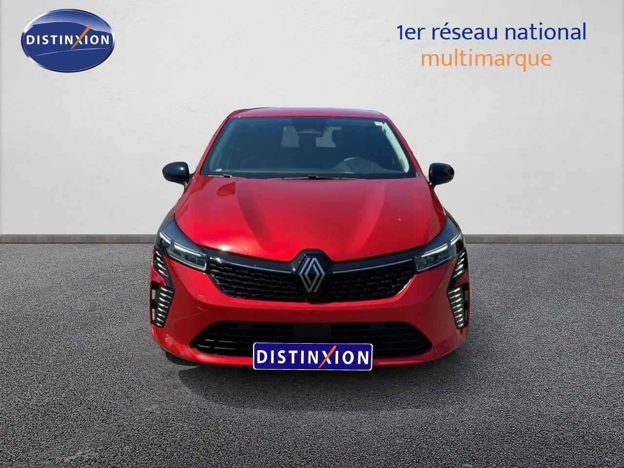 Vue frontale d'une Renault Clio 2025 rouge flamme métal avec calandre noire et feux LED verticaux allumés.