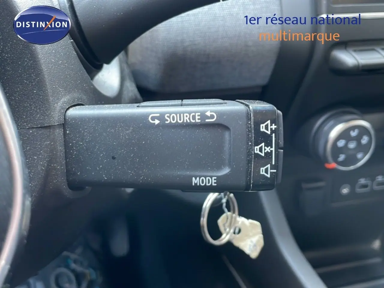 Gros plan sur la commande au volant de la Renault Clio 2025, avec touches source et mode visibles dans l’habitacle noir.