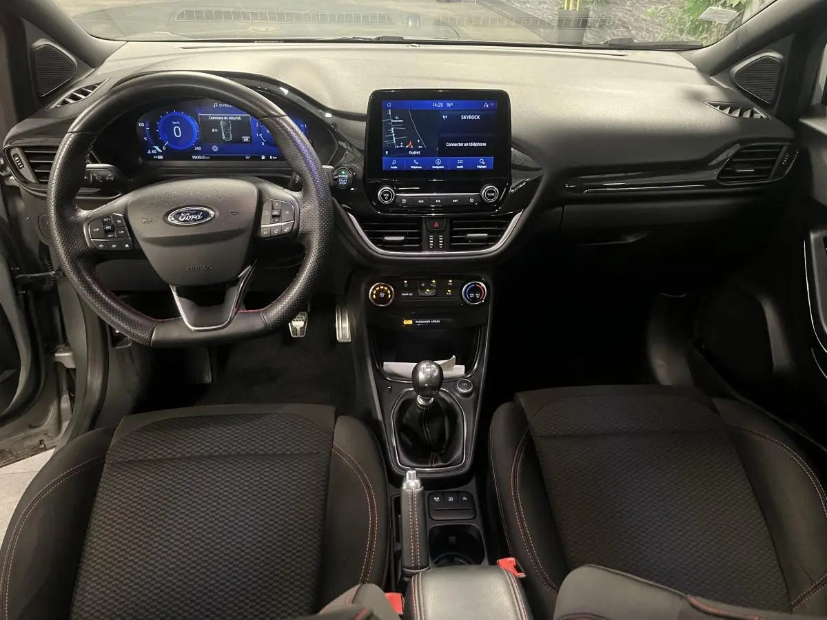 Vue intérieure avant du Ford Puma gris, tableau de bord noir avec écran tactile central et volant sport ST-Line.