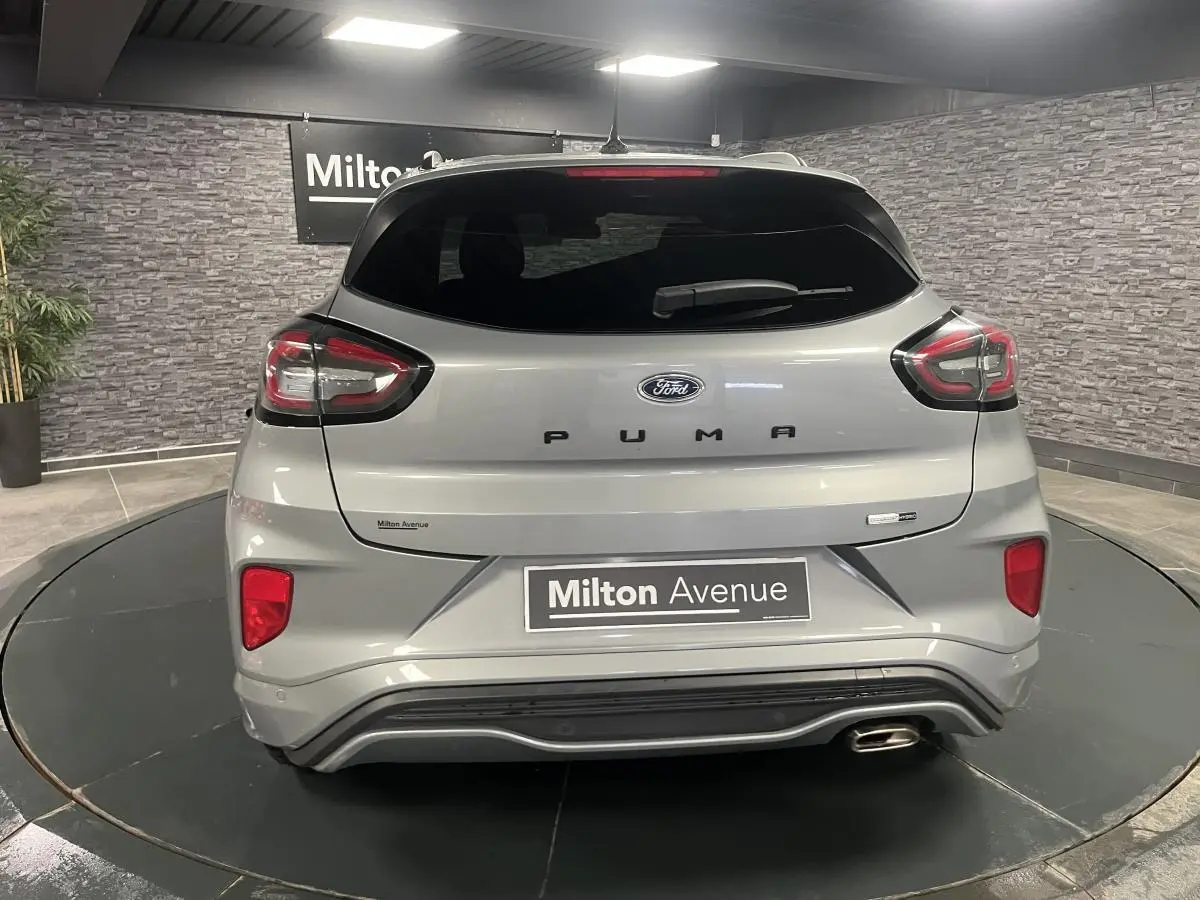 Vue arrière d'un Ford Puma gris métallisé avec feux LED et sortie d'échappement chromée dans un showroom.