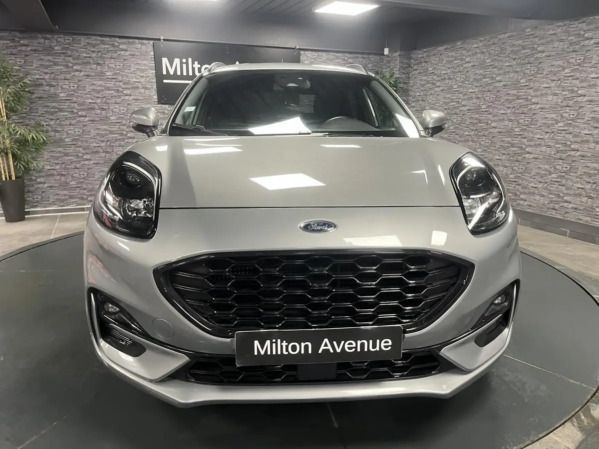 Vue avant d'un Ford Puma gris métallisé avec calandre noire et phares Full LED dans un showroom.