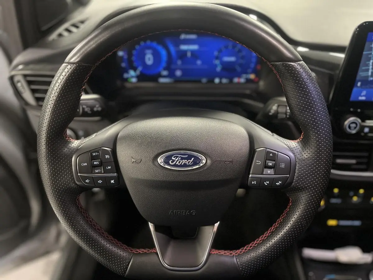 Volant cuir noir à surpiqûres rouges du Ford Puma ST Line 2021 avec commandes intégrées et tableau de bord numérique bleu.